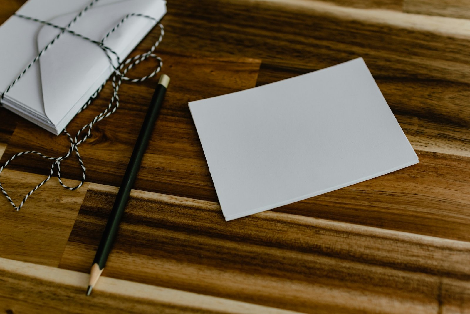 Blank postcard and black-and-gold pencil for direct mail campaign planning — photo by Kelly Sikkema on Unsplash